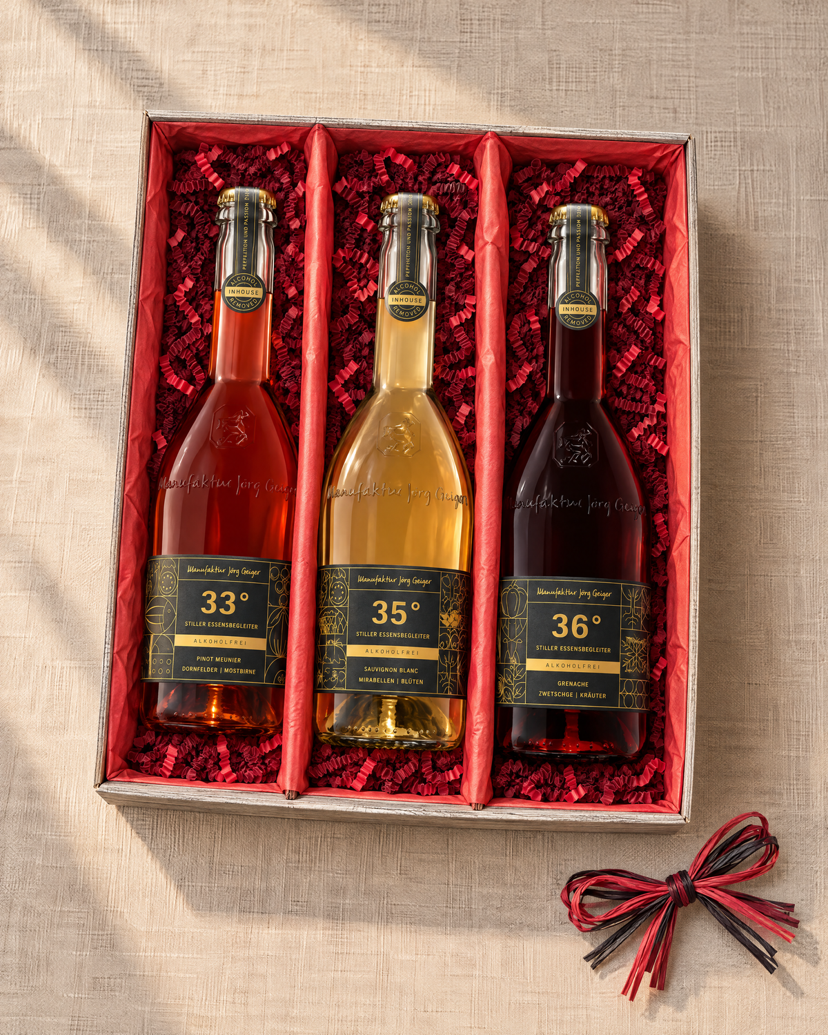 Grad°Wanderung Geschenkset mit drei alkoholfreien Cuvées in einer offenen 3er-Kartonage mit rotem Papier und rotem Sizzlepack